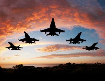 military planes flying in a V formation against a sunset sky