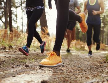 view of several runner's feet jogging along dirt trail
