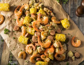 Lowcountry boil of shrimp, corn and other ingredients spread on brown paper 