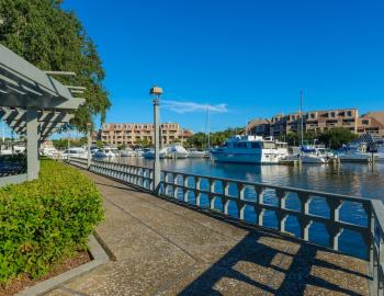 A walkway along a harbor with boats on a clear day
