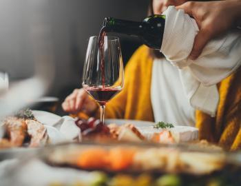A waiter pouring wine into a woman's glass at a restaurant table