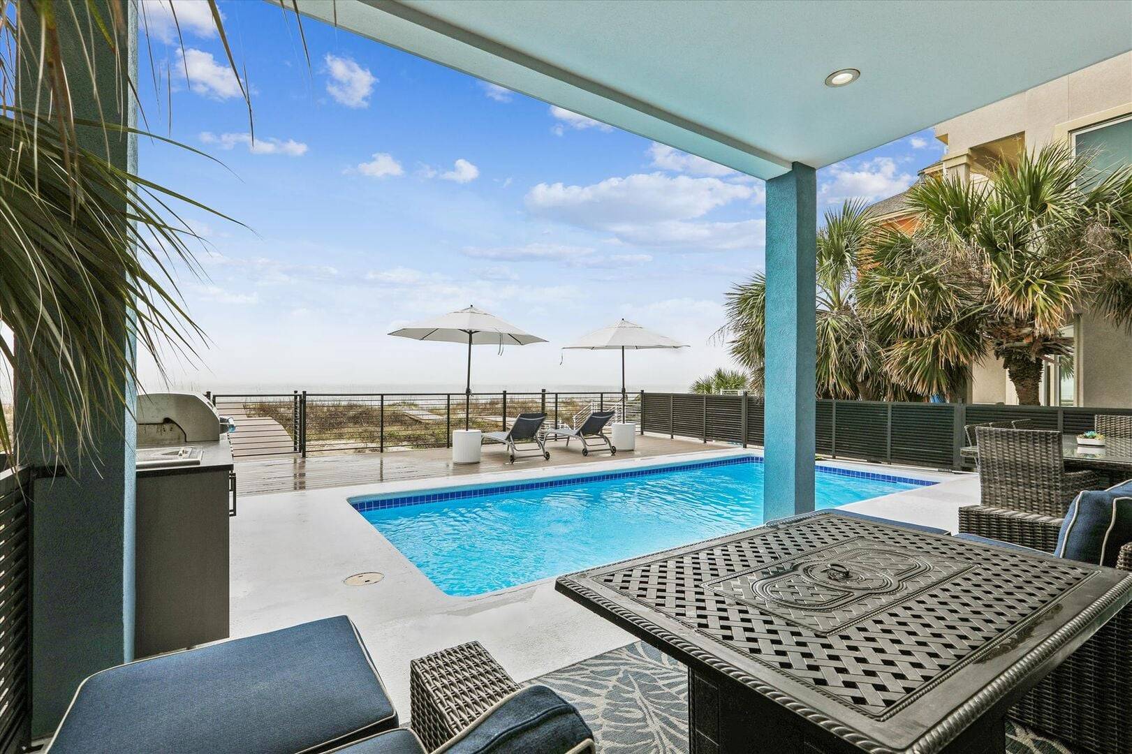 Vacation rental patio with private pool and ocean view in background