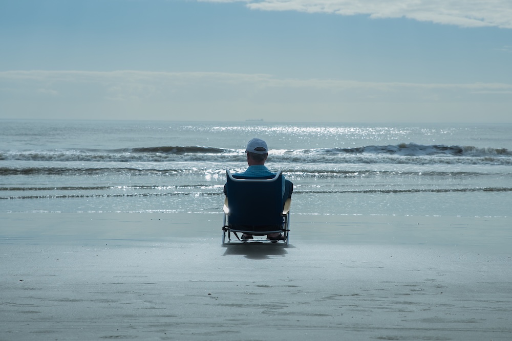 Man sitting in a beach chair at the shoreline