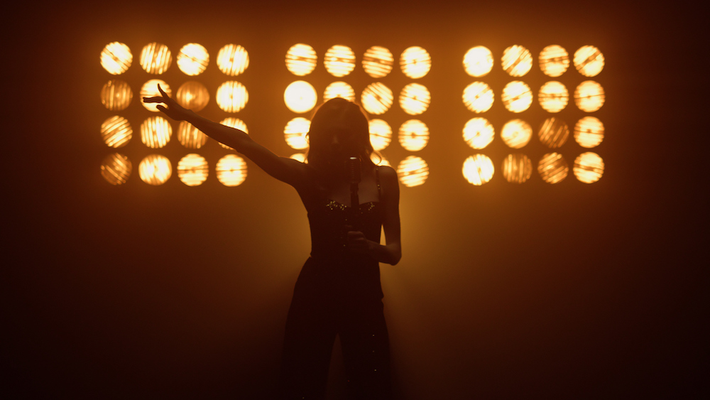 woman on stage shadowed by bright lights